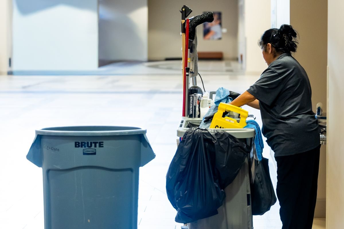 School custodian working at a cleaning cart in a hallway
